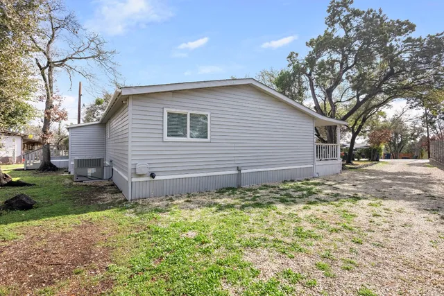 a backyard of a house with plants and large tree