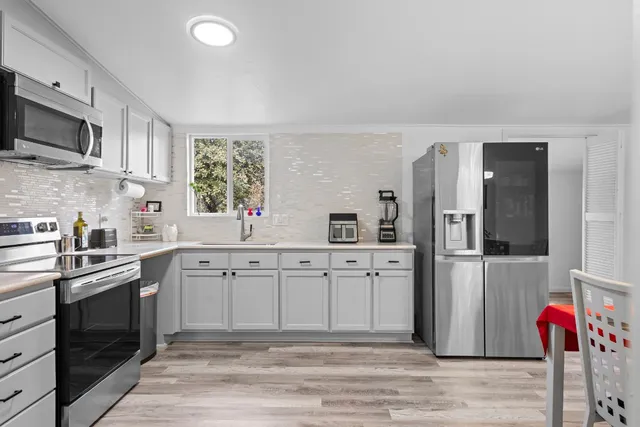 a spacious kitchen with stainless steel appliances granite countertop a stove sink and microwave