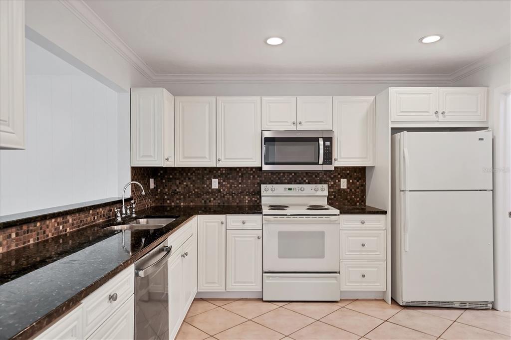 3930 Center Gate Circle, Unit 16 Sarasota, FL 34233 - Photo 11 of 30 a kitchen with white cabinets and appliances