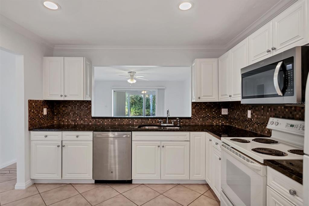 3930 Center Gate Circle, Unit 16 Sarasota, FL 34233 - Photo 12 of 30 a kitchen with white cabinets and appliances