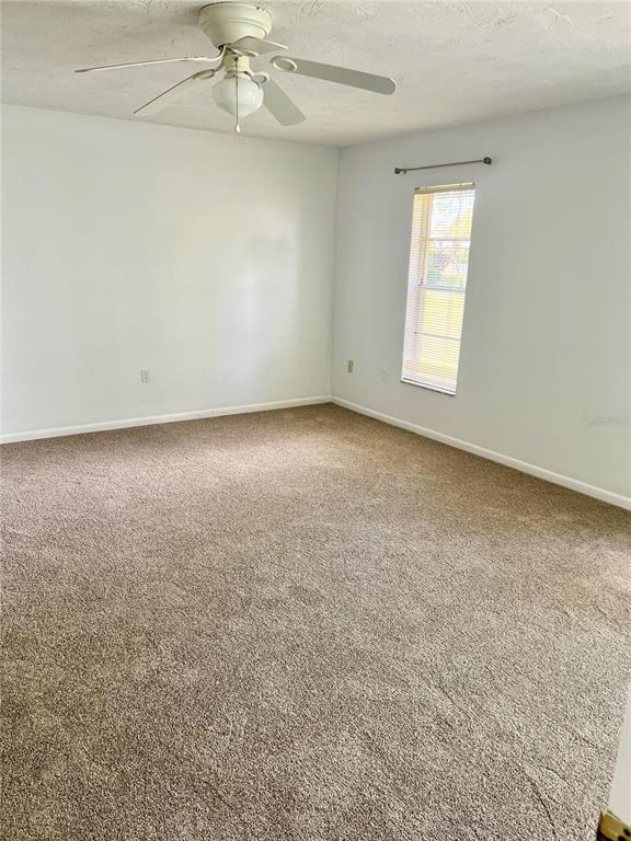 3930 Center Gate Circle, Unit 16 Sarasota, FL 34233 - Photo 17 of 30 an empty room with a chandelier fan and windows