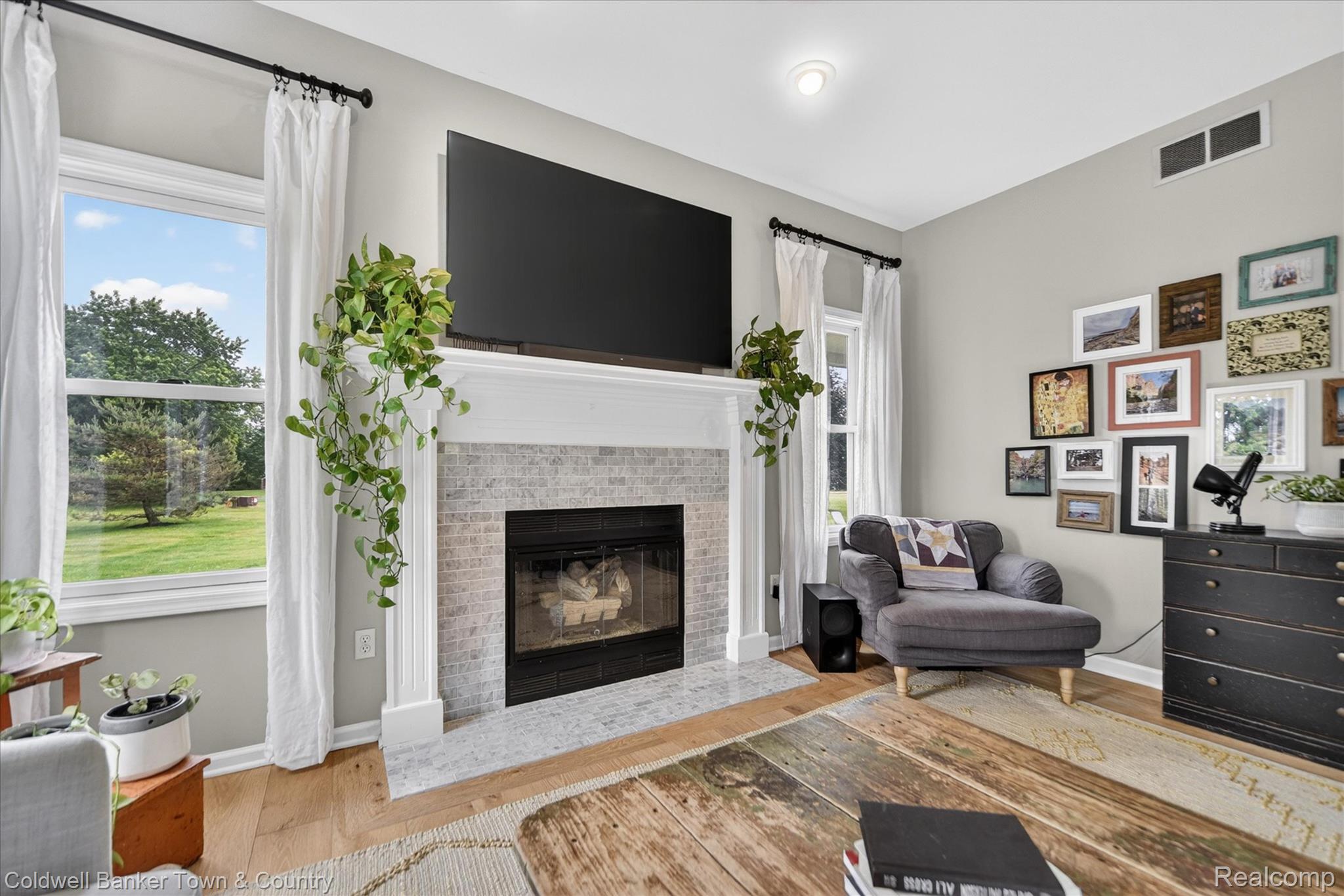 918 Gray Fox Court Howell, MI 48843 - Photo 17 of 84 Living area featuring a tiled fireplace with mantel, hardwood flooring, and neutral wall tones