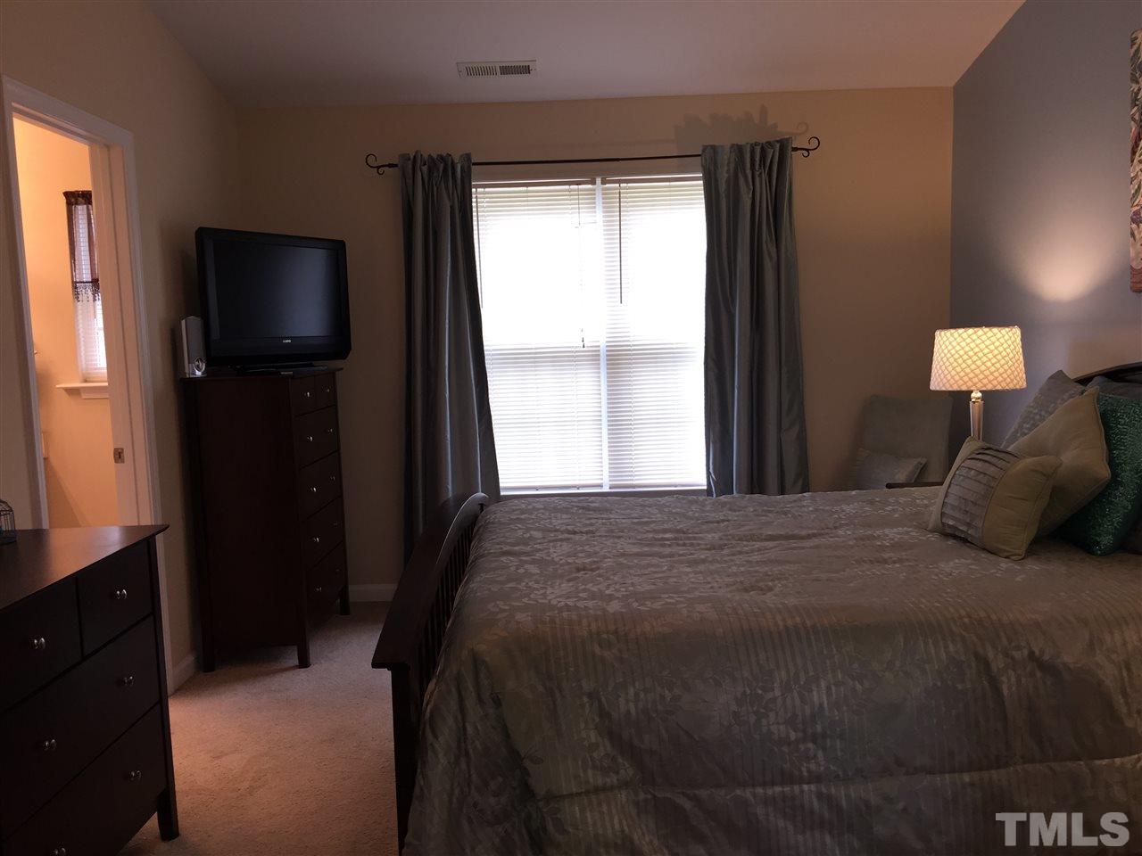 2136 Persimmon Ridge Drive Raleigh, NC 27604 - Photo 16 of 23 a bedroom with a bed and a flat tv screen on dresser