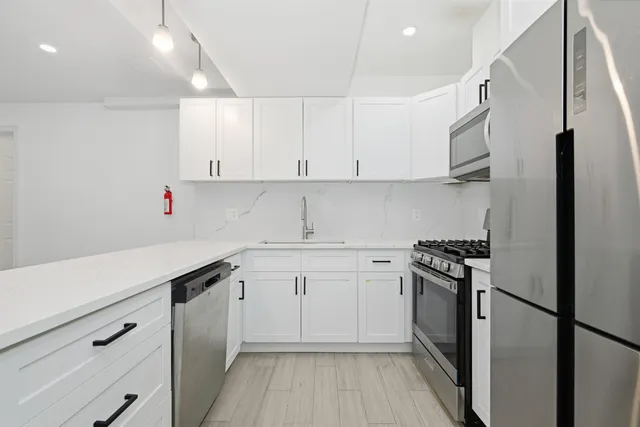 a kitchen with white cabinets and appliances