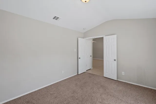 a view of an empty room with closet and windows