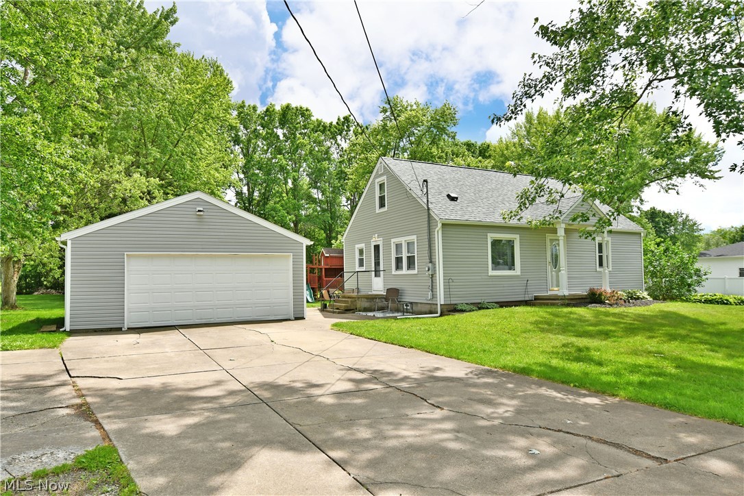 View of front facade featuring a front lawn, a garage, and an outdoor structure