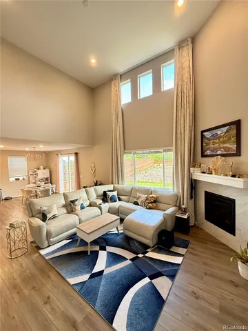 a living room with furniture kitchen view and a wooden floor