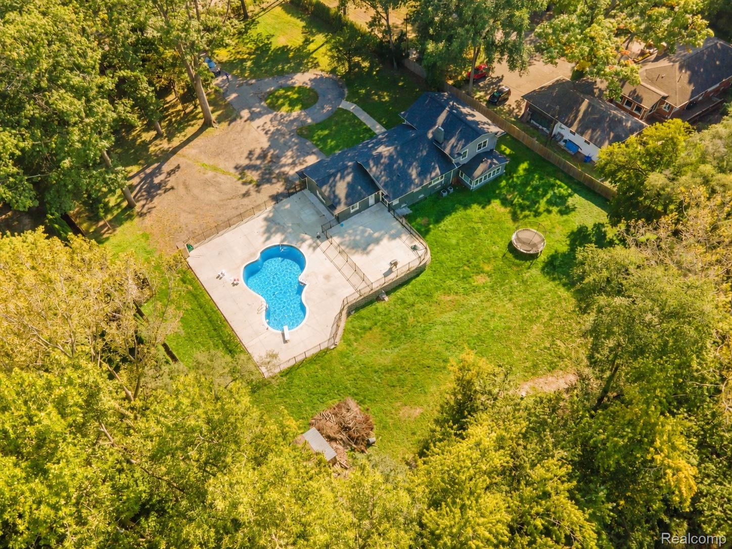 15879 Millar Road Clinton Township, MI 48036 - Photo 55 of 65 Expansive property featuring a freeform swimming pool with a surrounding concrete patio, a large grass area, and a gravel driveway