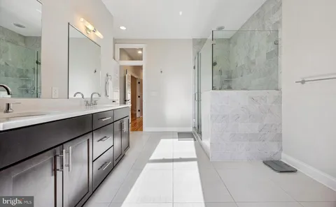 a bathroom with a double vanity sink a large mirror a shower and a bathtub