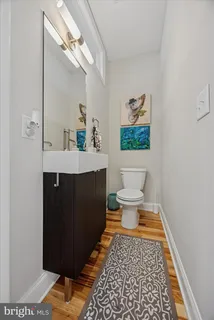 a bath room with a toilet a sink and mirror