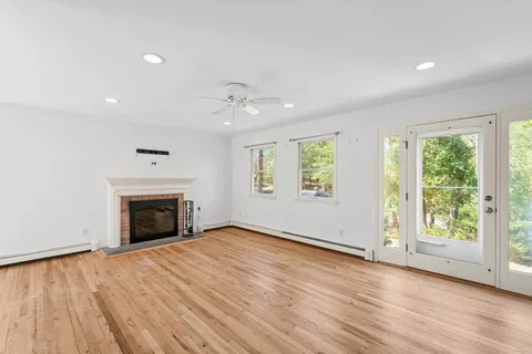 an empty room with wooden floor fireplace and windows