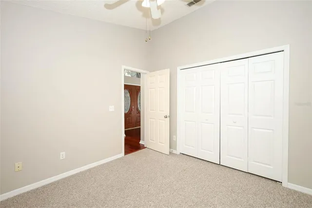 a view of a white house next to a yard with big trees and plants
