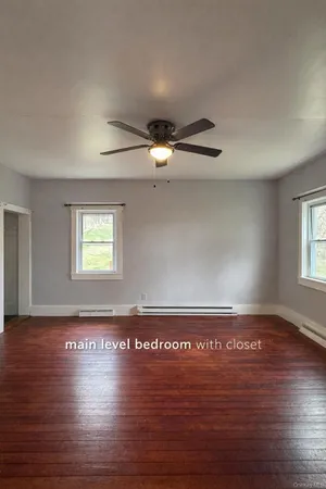 a view of an empty room with window and wooden floor