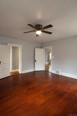 a view of an empty room with wooden floor and chandelier