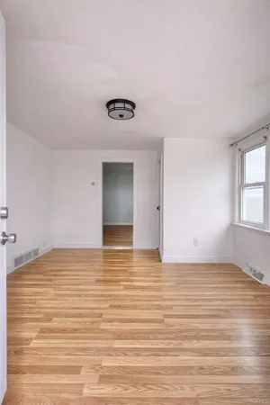 a view of an empty room with window and wooden floor