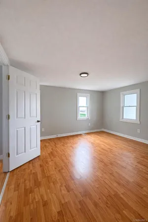 a view of empty room with window and wooden floor