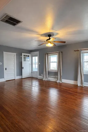 a view of an empty room with window and wooden floor