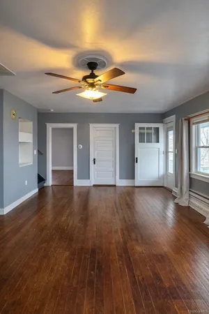 a view of an empty room with window and wooden floor