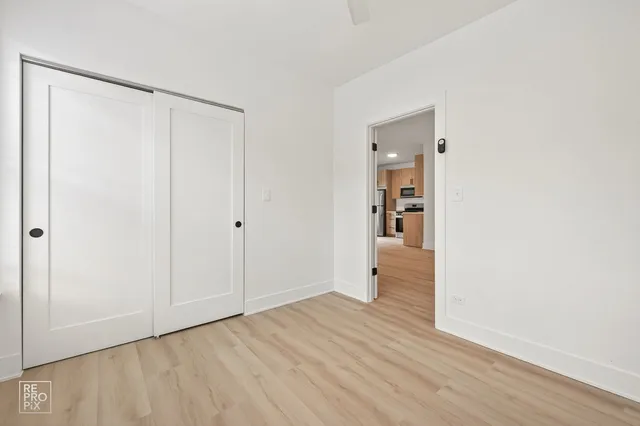 a view of an empty room with wooden floor and closet