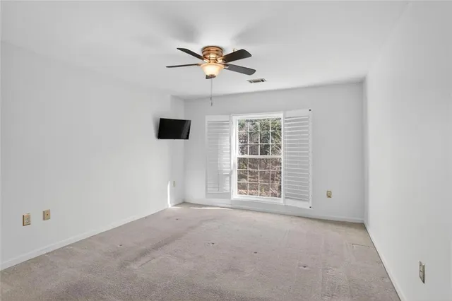 an empty room with windows and fan view