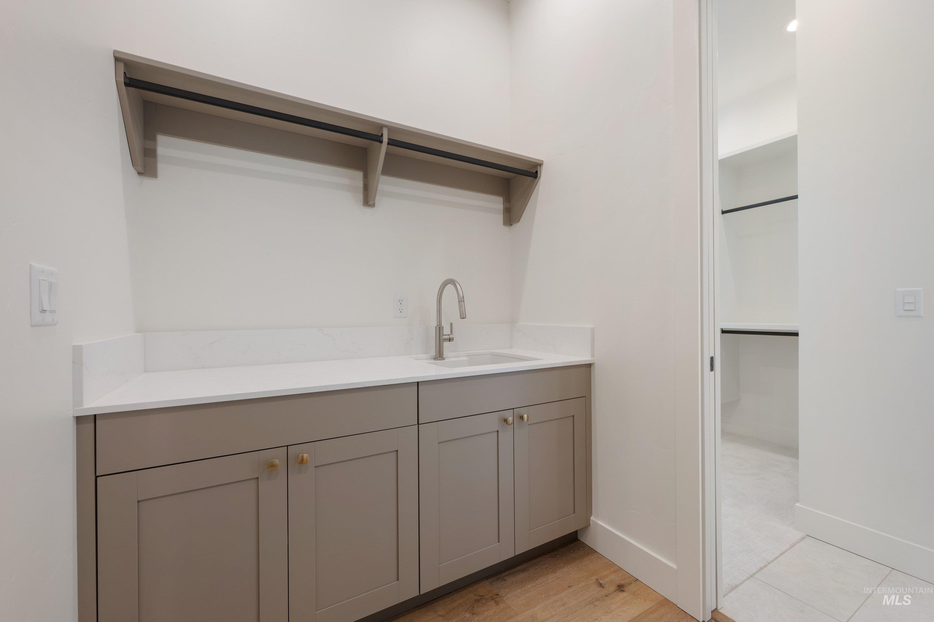 24763 Ardmore Court Caldwell, ID 83607 - Photo 31 of 50 Light gray cabinetry with gold-tone hardware, white countertop, and integrated sink with a brushed nickel faucet