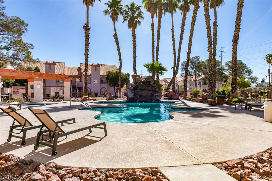 7570 West Flamingo Road, Unit 252 Las Vegas, NV 89147 - Photo 38 of 44 A tranquil community pool area, adorned with swaying palms, offers a refreshing escape and a rock waterfall feature.