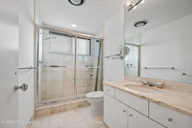 a bathroom with a granite countertop sink a toilet and shower