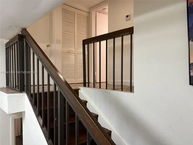 a view of staircase with lots of frames on wall and a window