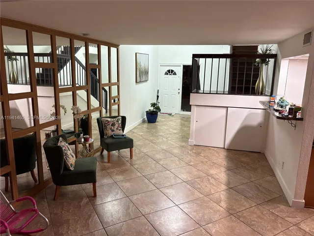a living room with couches and large potted plants with wooden floor