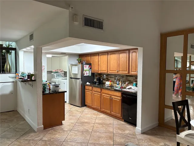 a kitchen with stainless steel appliances kitchen island granite countertop a refrigerator and a stove top oven