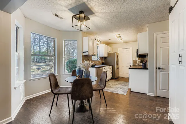 a view of a dining room and livingroom with furniture wooden floor a chandelier