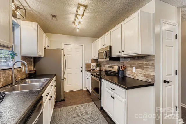 a kitchen with stainless steel appliances granite countertop a sink stove and refrigerator