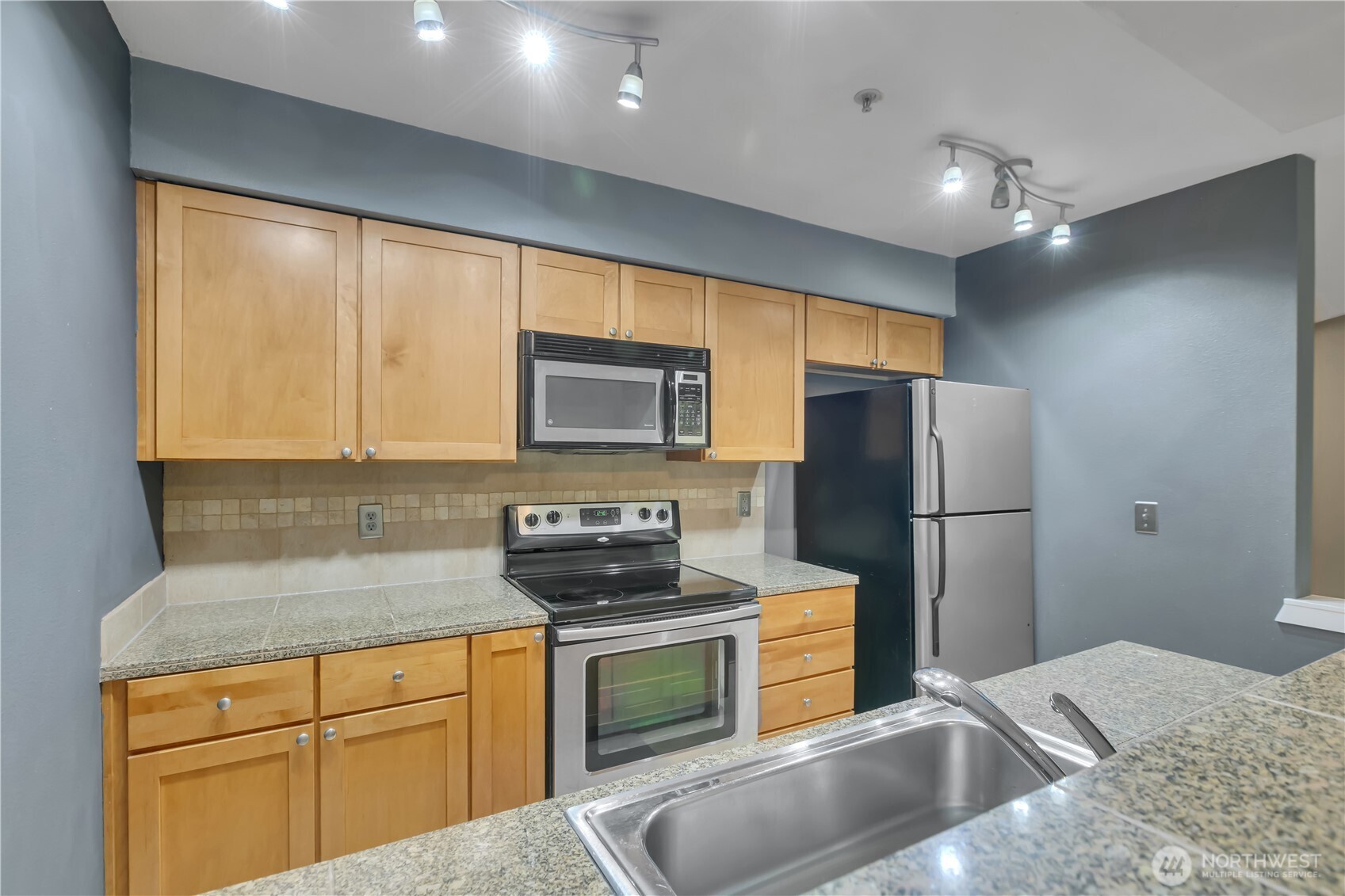 18930 Bothell Everett Highway, Unit B304 Bothell, WA 98012 - Photo 12 of 35 a kitchen with stainless steel appliances granite countertop a refrigerator sink and microwave
