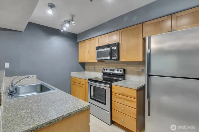 a kitchen with stainless steel appliances granite countertop a sink a stove and refrigerator