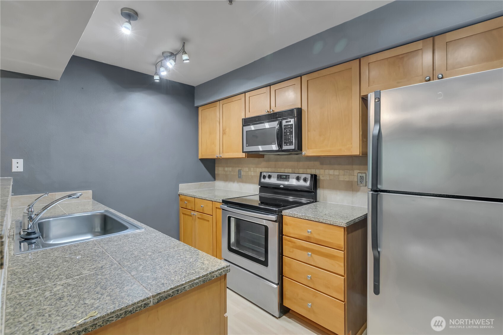 18930 Bothell Everett Highway, Unit B304 Bothell, WA 98012 - Photo 13 of 35 a kitchen with stainless steel appliances granite countertop a sink a stove and refrigerator