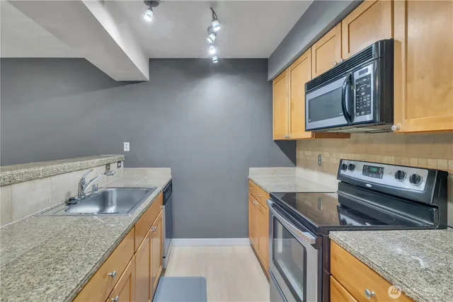 a kitchen with stainless steel appliances granite countertop a sink dishwasher stove and oven