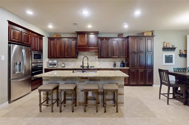 a kitchen with kitchen island granite countertop wooden cabinets a refrigerator and a refrigerator