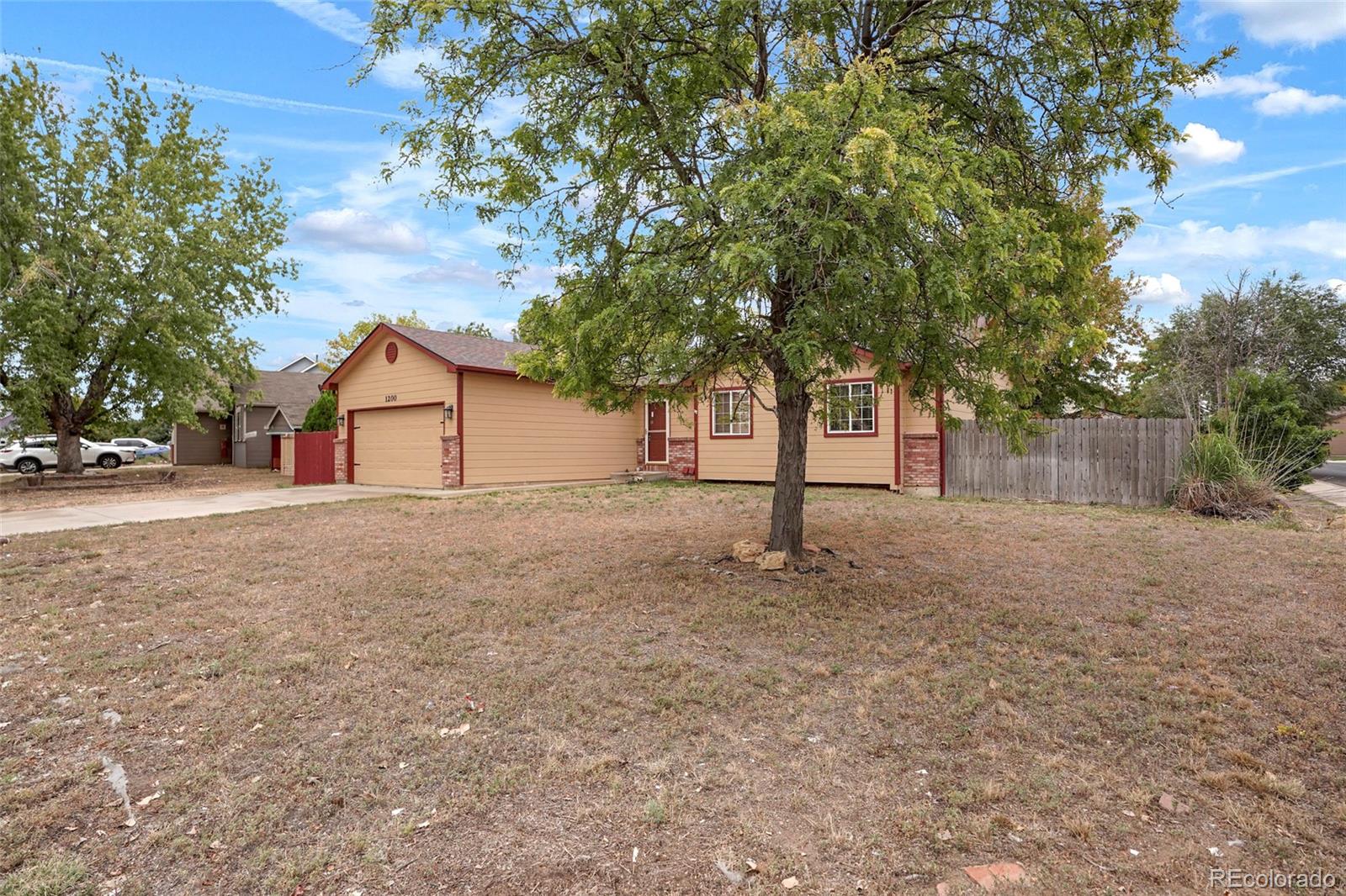 1200 7th Street Fort Lupton, CO 80621 - Photo 16 of 17 a backyard of a house with large trees and wooden fence