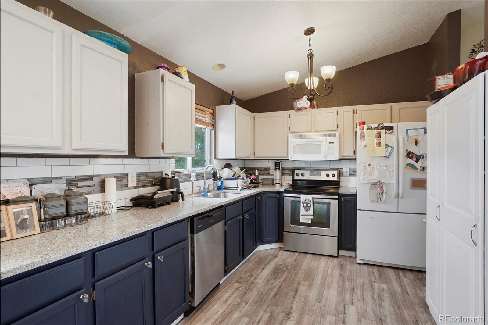 1200 7th Street Fort Lupton, CO 80621 - Photo 3 of 17 a kitchen with a sink dishwasher a refrigerator a stove and white cabinets with wooden floor