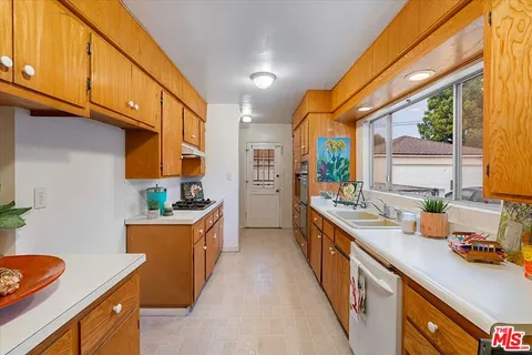 a kitchen with granite countertop a sink a counter top space and stainless steel appliances