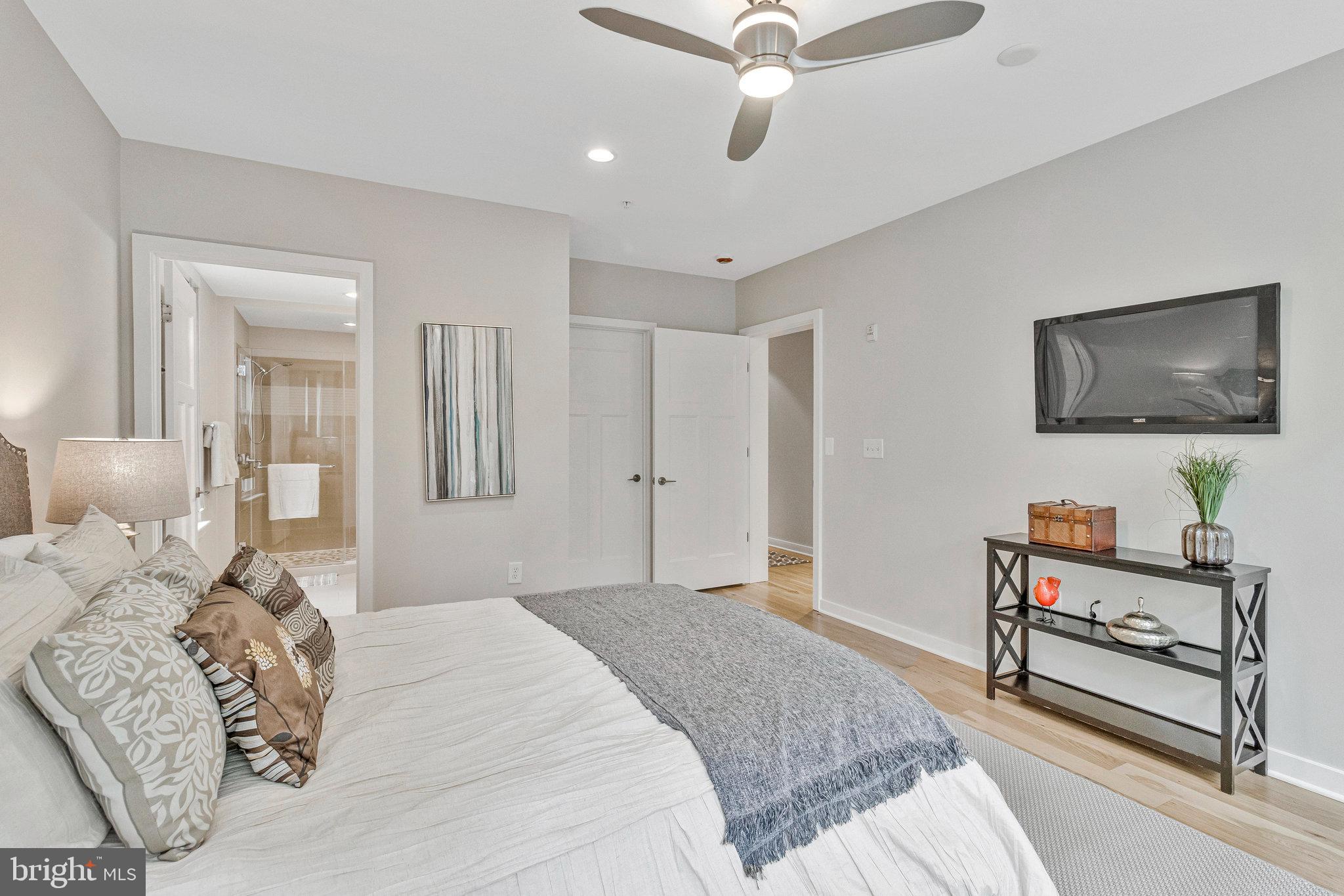 1610 North Queen Street, Unit 211 Arlington, VA 22209 - Photo 21 of 43 a bedroom with a bed a bookshelf and a flat screen tv