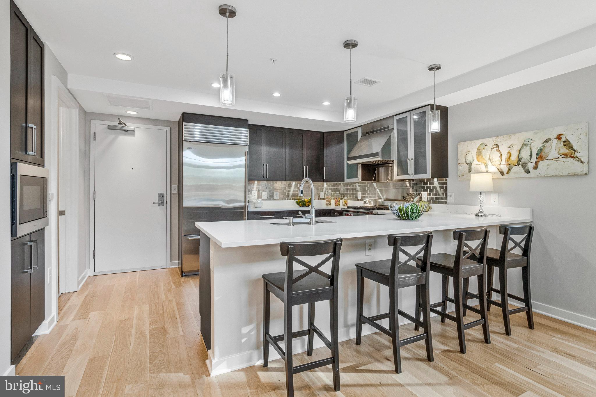 1610 North Queen Street, Unit 211 Arlington, VA 22209 - Photo 8 of 43 a kitchen with kitchen island a dining table chairs cabinets and stainless steel appliances