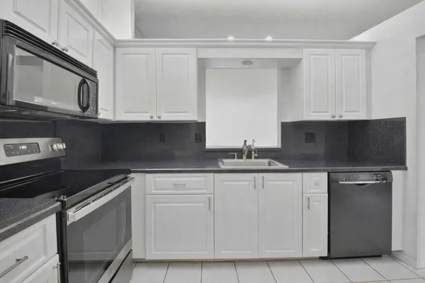 a kitchen with granite countertop white cabinets and stainless steel appliances