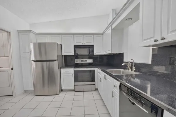 a kitchen with a refrigerator sink and cabinets