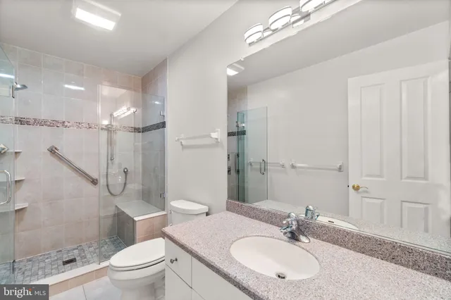 a bathroom with a granite countertop sink a toilet a mirror and shower