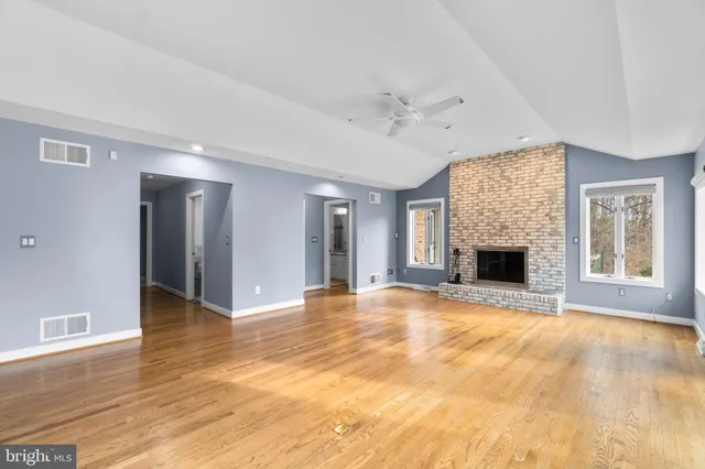 a view of an empty room with wooden floor fireplace and a window