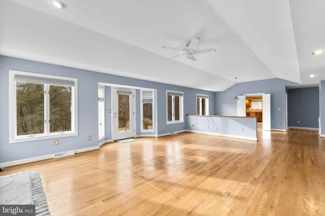 a view of an empty room with window and wooden floor