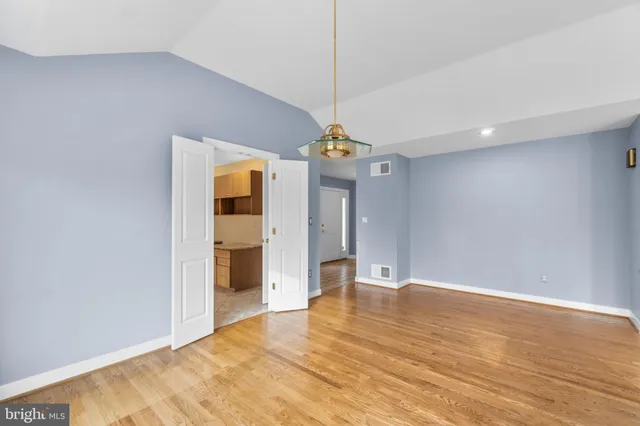 a view of an empty room with window and wooden floor