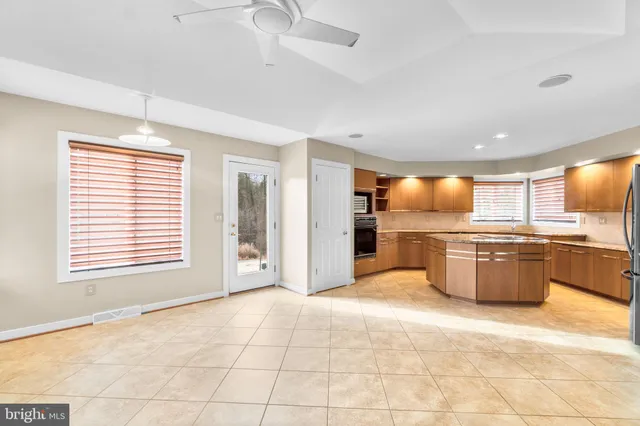 a view of kitchen with stainless steel appliances wooden floor and large window