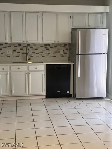 a kitchen with granite countertop a refrigerator a stove a sink and cabinets
